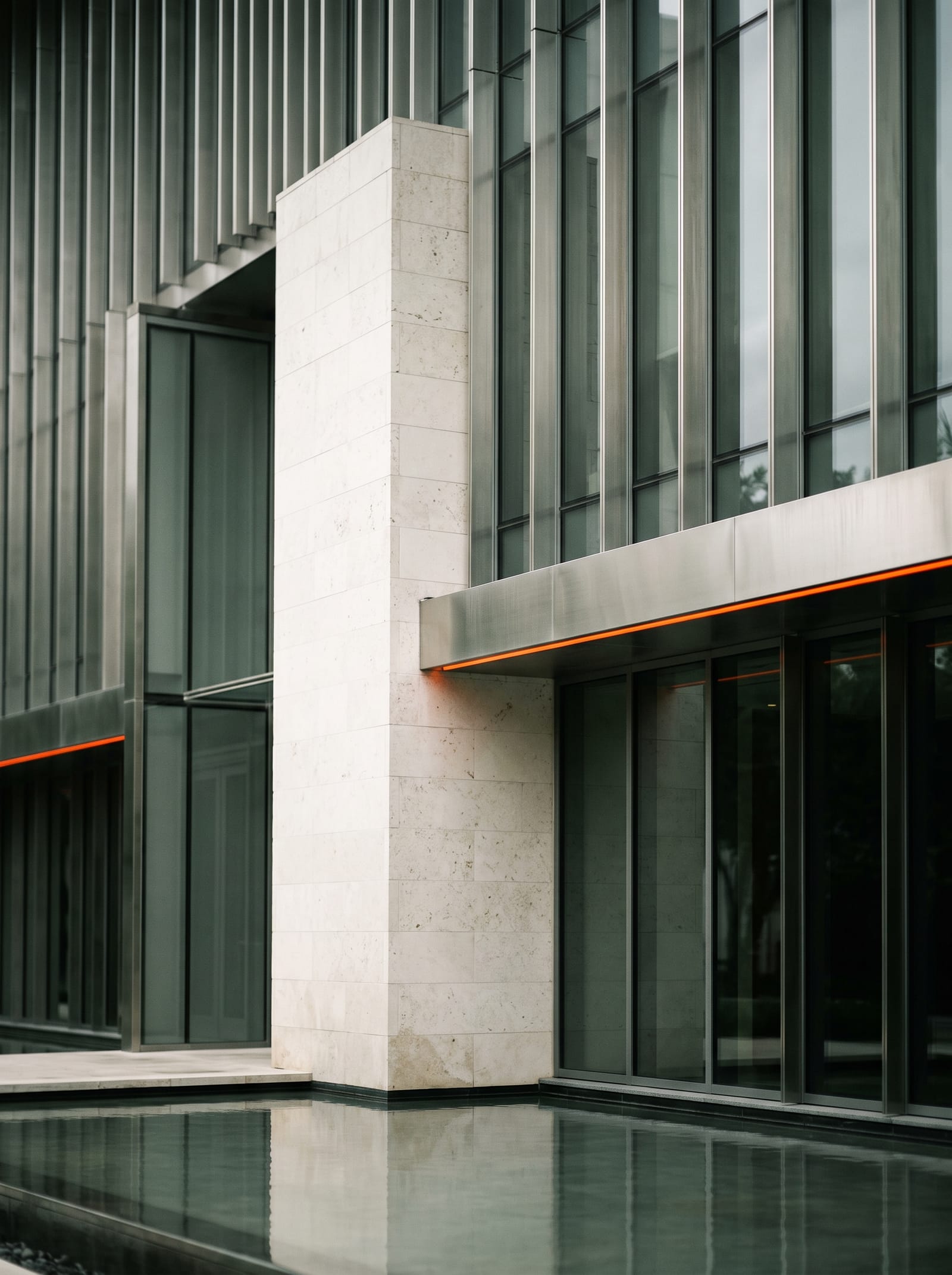 Limestone and smoked glass facade above a still reflecting pool