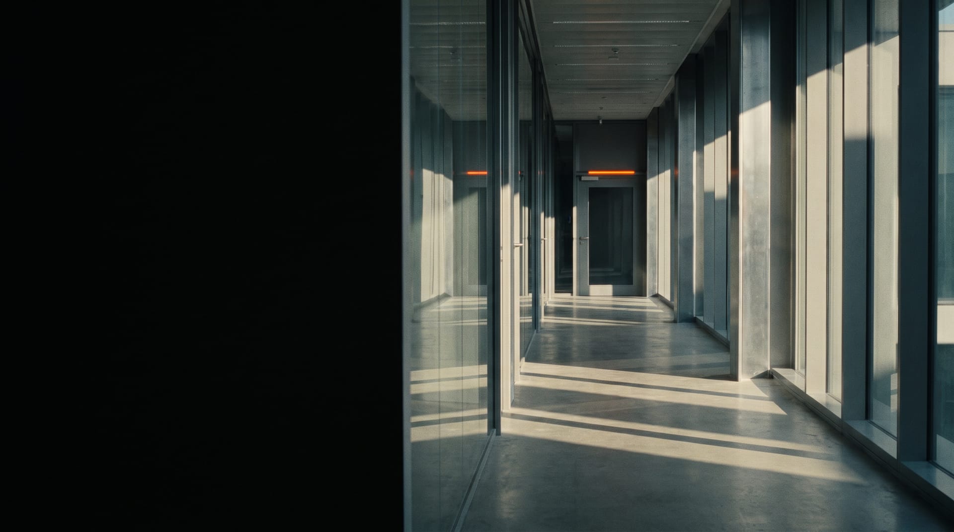 Smoked glass corridor with a single orange indicator light