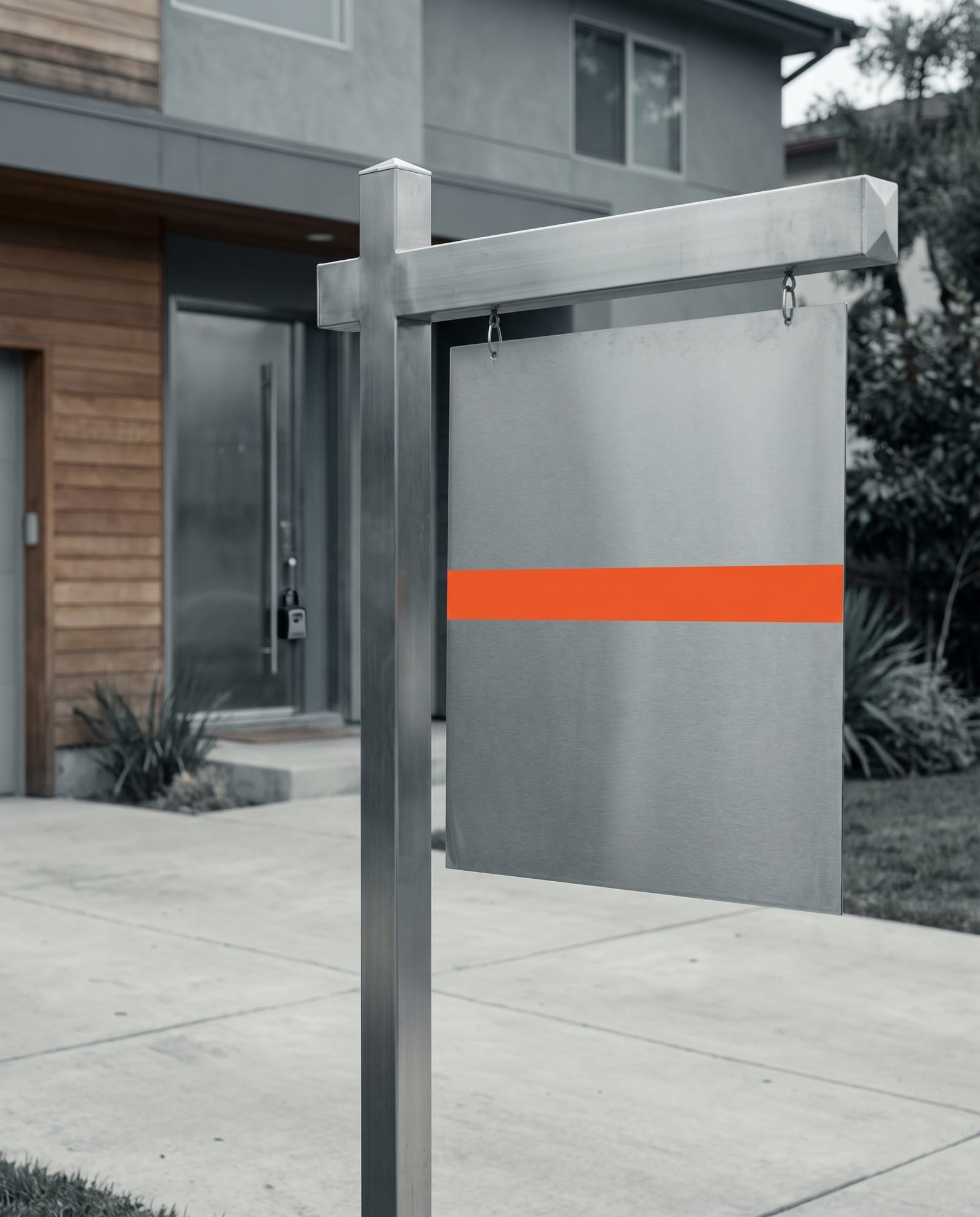 A blank steel for-sale sign with an orange stripe in front of a modern South Florida home